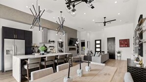 Une cuisine moderne dotée d’un îlot central, d’un coin repas avec des chaises et d’un salon avec un canapé et une télévision.