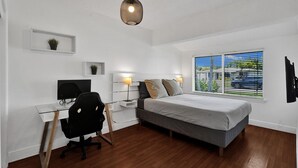 Ein Schlafzimmer mit Bett, Schreibtisch, Stuhl und einer Pendelleuchte.