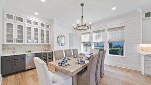 A modern kitchen with white cabinetry, a dining table set for six, and a chandelier. - Luxurious 4-BR Home w/ Private Pool & Beach Access – Golf Cart & Bikes Included (Santa Rosa Beach)