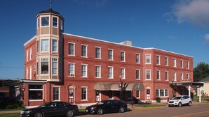 A red brick building with a corner tower, a covered entrance, and a sign for 'Hotel Anderson'. - AH #11 · AH #11 Queen Suite w/Tub/Shower (Wabasha)