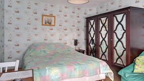 Een slaapkamer met een bed, een kledingkast, een lamp en een stoel.