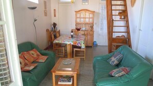 A cozy living room with two green sofas, a wooden coffee table, and a dining area with a wooden cabinet and table. - Ref 518 - Soulacaise near downtown (SOULAC SUR MER)