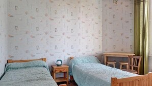 A room with two wooden beds, a small wooden table, a nightstand, and a ceiling fan. - Ref 518 - Soulacaise near downtown (SOULAC SUR MER)