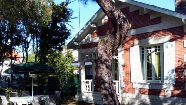 A brick building with a porch, outdoor seating, and a large tree. - Ref 518 - Soulacaise near downtown (SOULAC SUR MER)