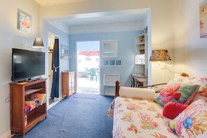 A cozy room with a television on a wooden stand, a bed with colorful bedding, and a view of the outside.