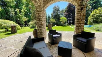Un espace extérieur aménagé avec des piliers en pierre, un sol en pierre et entouré de verdure.