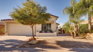 Ein Wohnhaus mit Garage, Auffahrt und einem kleinen Garten mit Steinen und Topfpflanzen.
