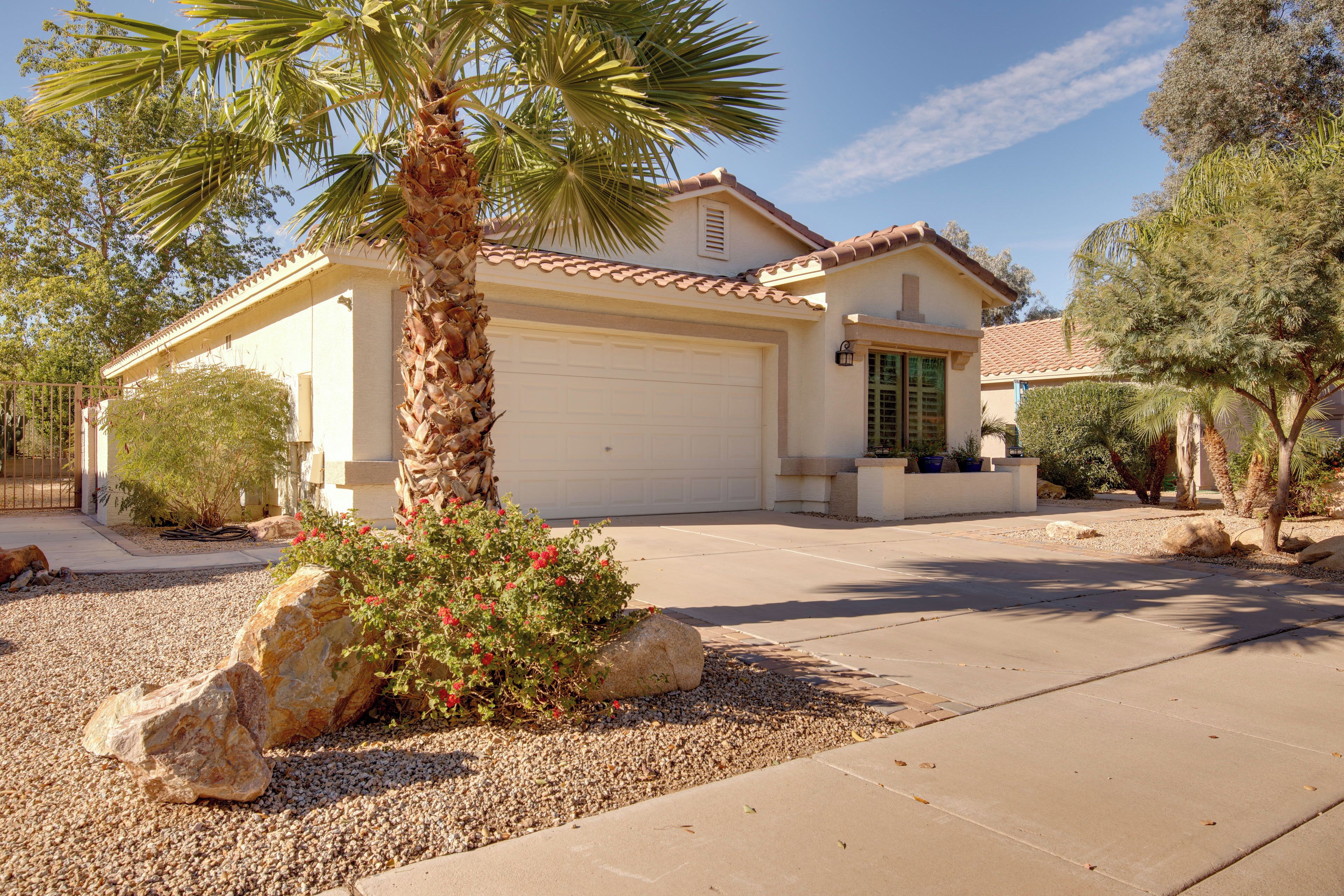 A house with a garage, a palm tree, and a rock garden.