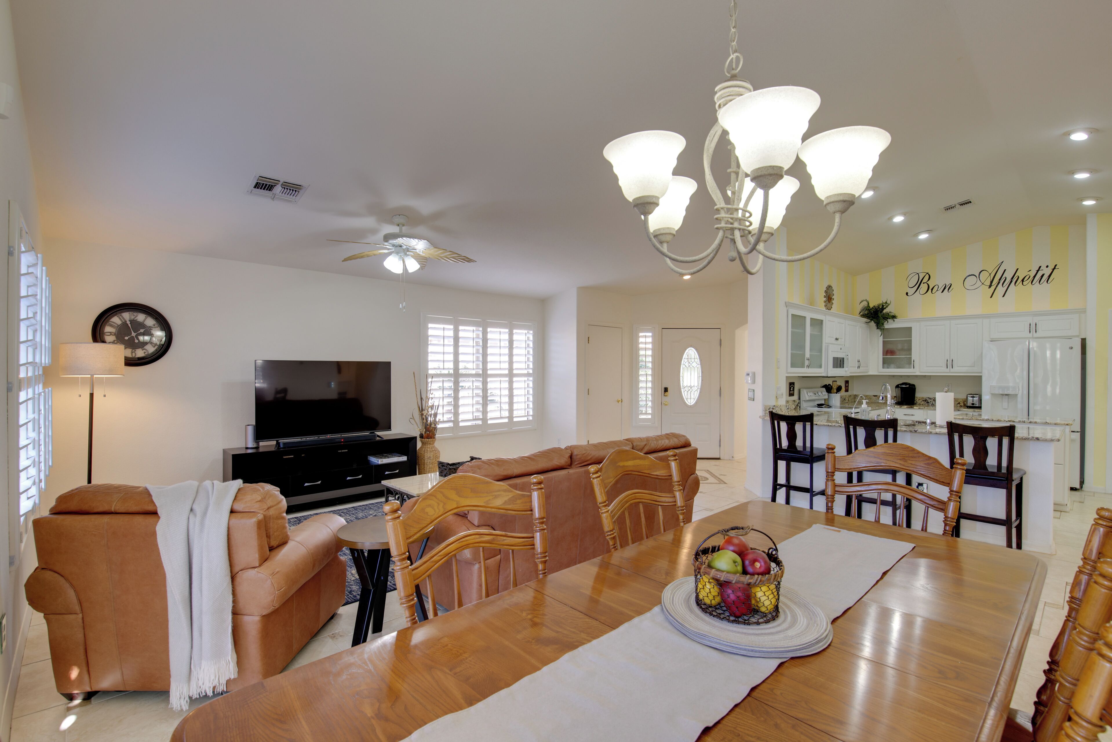 A spacious living room with a large wooden dining table, a comfortable sofa, and a television.