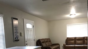 A living room with a brown leather sofa, a white dining table with benches, and a white door. - 3.2 miles to the beaches and Bay, Cute Florida Cottage (Fort Walton Beach)