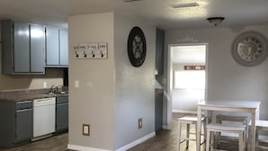 A spacious living area with a brown leather couch, a kitchen with grey cabinets, and a dining area with white furniture. - 3.2 miles to the beaches and Bay, Cute Florida Cottage (Fort Walton Beach)