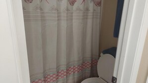 Ein Badezimmer mit Toilette, einer Duschvorhang mit floralem Muster und einem Handtuch an der Wand.