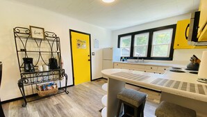 Une cuisine compacte dotée d’un îlot central, d’un coin café et d’une porte jaune.