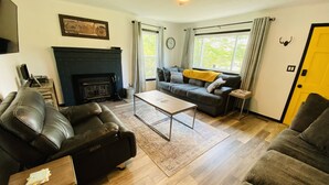 Un salon avec une cheminée, des canapés en cuir, une table basse et une porte jaune.