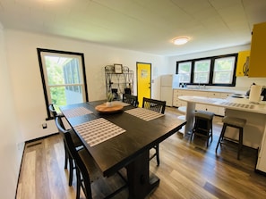 A modern kitchen with a dining area, featuring a wooden table, chairs, and a central island with a sink.