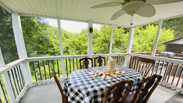 Une terrasse extérieure couverte, avec une nappe à carreaux, des chaises en bois et une tour de Jenga.