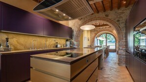 Una cucina moderna con isola centrale, arco in pietra e vista sull'esterno.