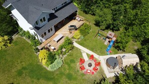 A two-story house with a deck, a patio with outdoor furniture, a play area with a slide, and a barbecue grill. - Lake Life(Waterfront) (Seven sisters falls)
