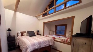 A bedroom with a bed, a nightstand, a wooden cabinet, and a window with a view. - Small cabin on private 400 acre mountaintop farm! (Hinton)