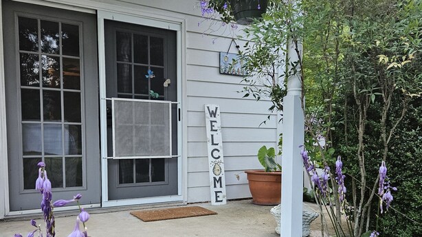 Une maison avec une véranda, un panneau d’accueil et une porte munie d’une moustiquaire.
