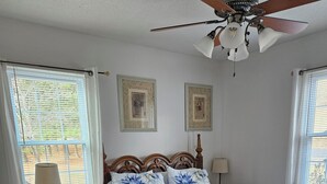 Une chambre à coucher avec un lit en bois, une table de chevet, un bureau et un ventilateur de plafond.