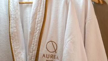 Una bata blanca con ribete dorado y el texto 'AUREA HOTELS' bordado.