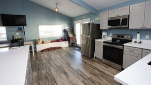 A modern kitchen with stainless steel appliances, light blue walls, and wooden flooring.