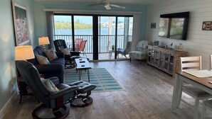 A spacious living room with a large sliding glass door leading to a balcony with a view of the ocean. There is a comfortable seating area with a sofa, chairs, and a coffee table. - Waterfront condo located in the waterfront paradise of Bokeelia (Bokeelia)