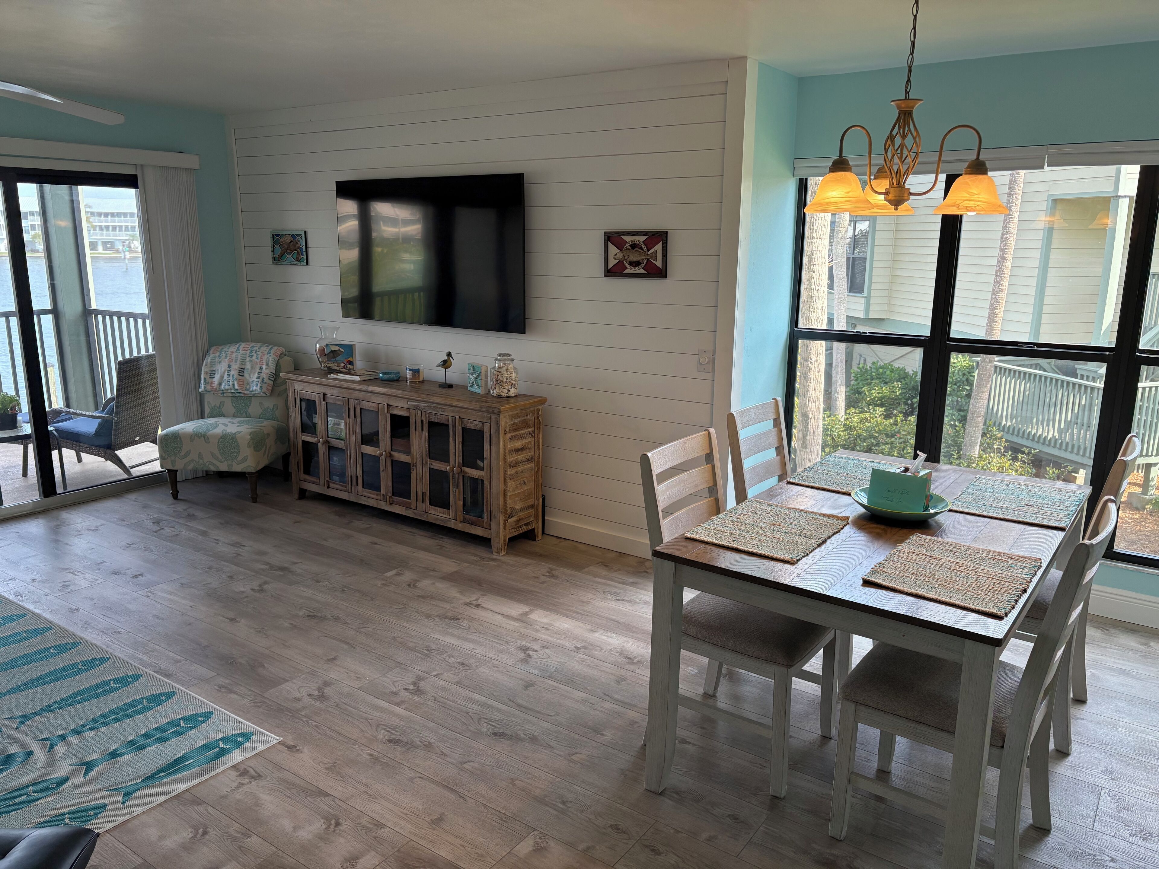 Un coin repas avec une table en bois, des chaises et un téléviseur fixé au mur.