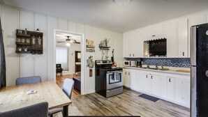 Eine moderne Küche mit weißen Schränken, einem schwarzen Kühlschrank und einem Holztisch.