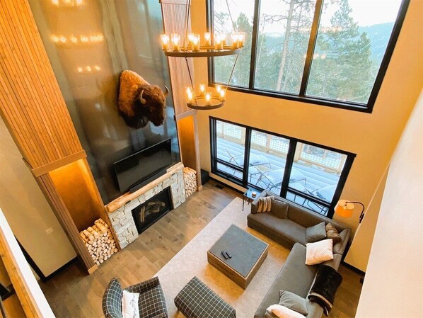 A modern living room with a fireplace, a mounted animal head, a large TV, and a sofa.