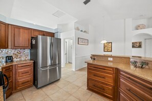 Enjoy cooking in this well-equipped kitchen with a refrigerator, oven, and wooden cabinets.