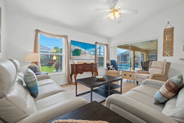 Relax in a cozy seating area with two sofas and a coffee table, surrounded by a large window offering a view of the outdoors.