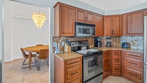 Una cocina con gabinetes de madera, una estufa de acero inoxidable, un microondas y una mesa de comedor con sillas.