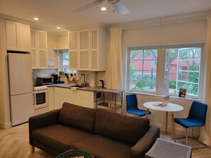 Cozy living space with a kitchenette, sofa, and dining area, offering a view of the outside.