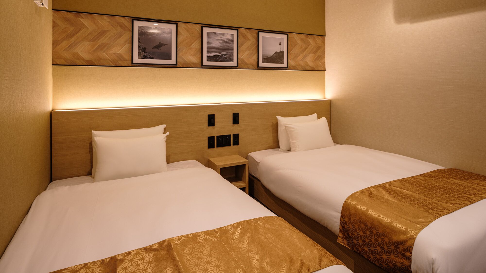 A hotel room with two beds, a wooden headboard, and three framed pictures on the wall.