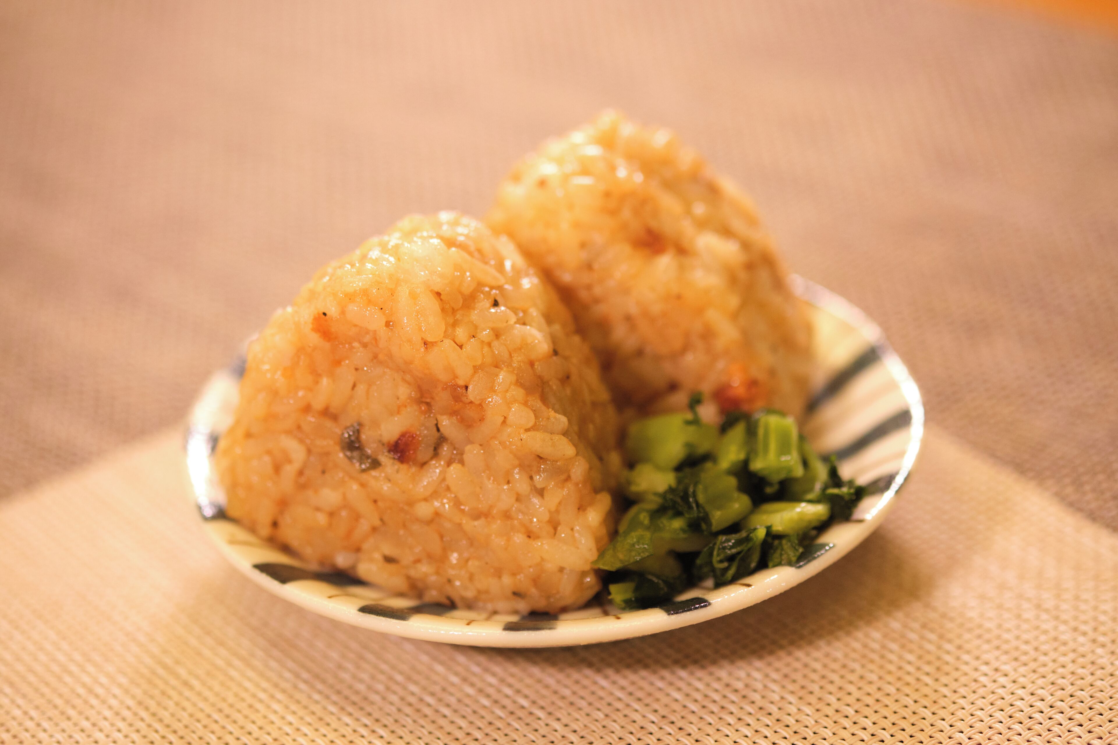 A plate with two rice balls and some greens.