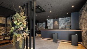 A reception area with a modern design, featuring a reception desk, a large decorative plant, and a stone wall. - HOTEL SUI HAMAMATSU (Hamamatsu)