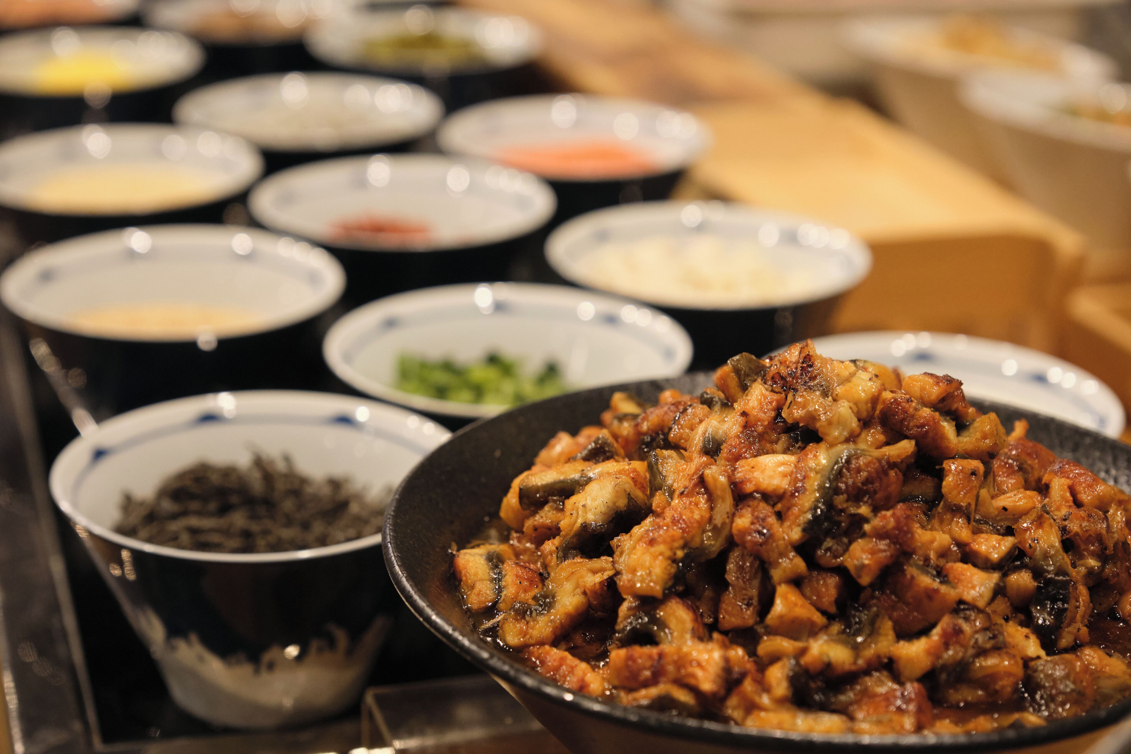 A variety of dishes in bowls, including a prominent bowl of stir-fried meat.