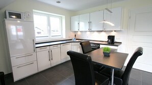 A modern kitchen with white cabinets, a black countertop, and a dining table with chairs.