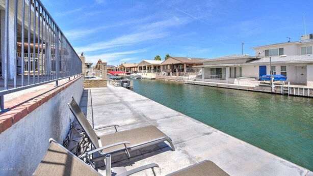 A waterfront property with a dock, a covered seating area, and a building with a red roof. - Parker Keys--Two Houses from the River (Parker)