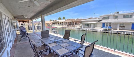 A covered outdoor area with a table and chairs, a ceiling fan, and a view of a marina with boats.