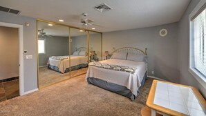 A bedroom with two beds, a large mirror, a ceiling fan, and a window with blinds. - Parker Keys--Two Houses from the River (Parker)