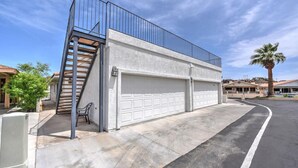 A residential garage with a white exterior, a metal staircase, and a white garage door. - Parker Keys--Two Houses from the River (Parker)