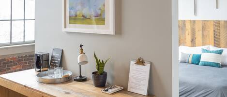A wooden desk with a framed painting, a potted plant, a coffee machine, and a clipboard.