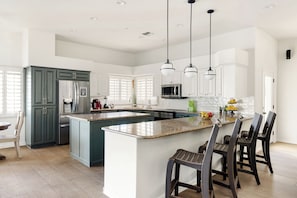 A modern kitchen with a central island, dark cabinets, and pendant lighting.