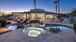 Una piscina con jacuzzi, palmeras y mobiliario de exterior.