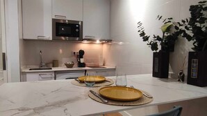 Una cucina moderna con mobili bianchi, un forno a microonde, un lavello e un'area pranzo con piatti e posate gialli.