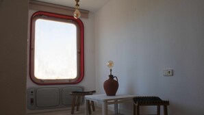 Een kamer met een groot raam, een tafel, een stoel en een vaas met een gloeilamp.