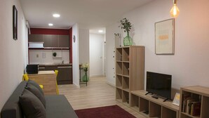 Een moderne woonkamer met een grijze bank, een rood kleed, een televisie en een boekenkast.